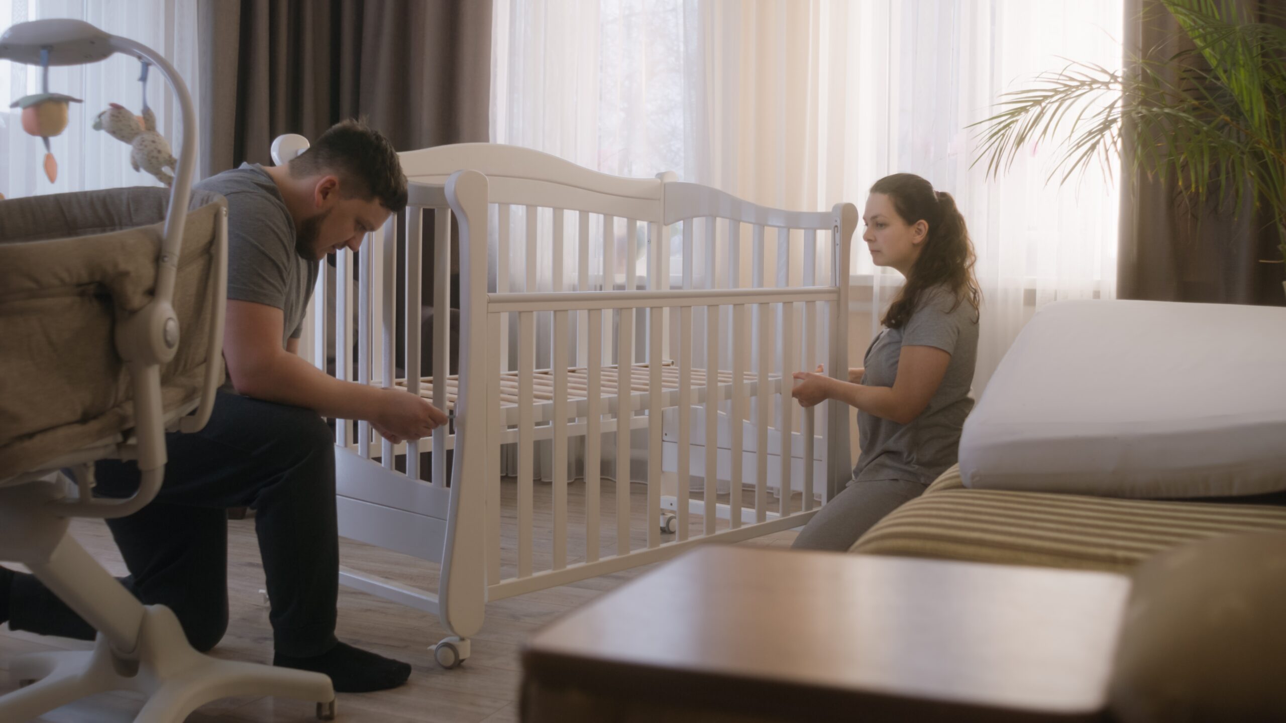 A couple disassembling a crib for storage