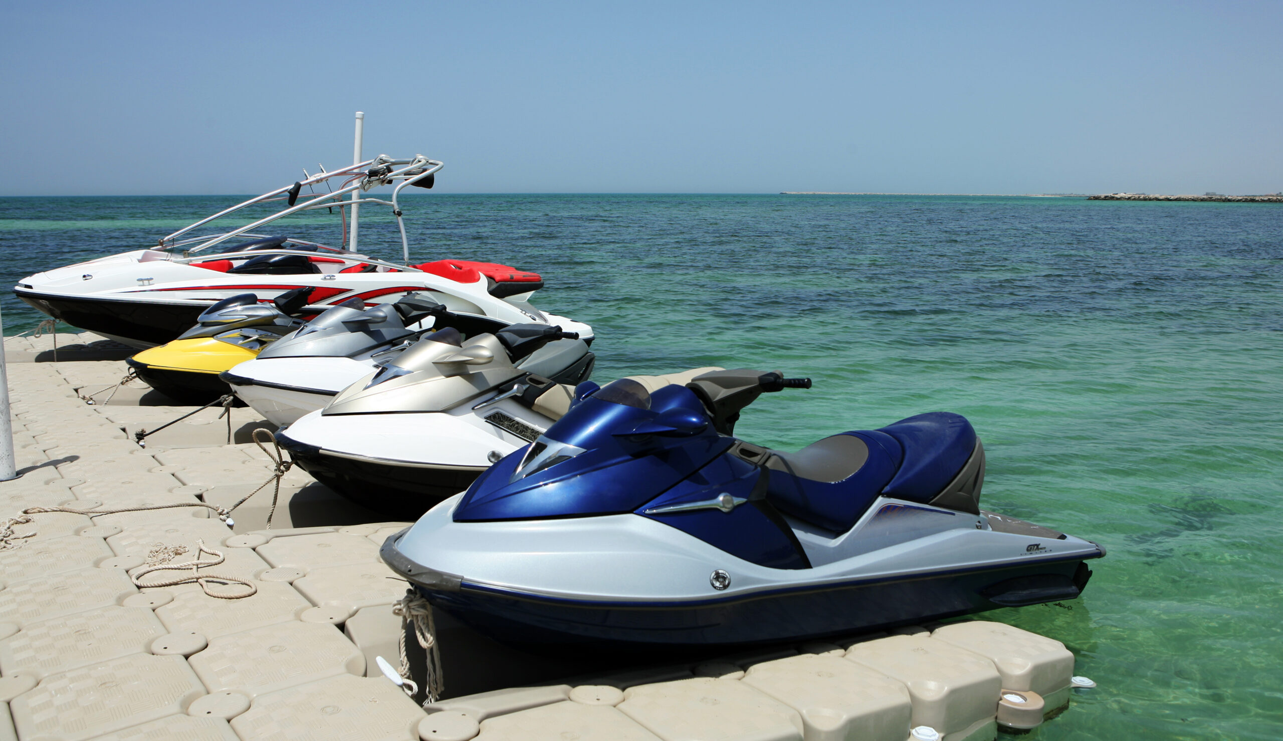 Jet skis and a speedboat tied up in a marina