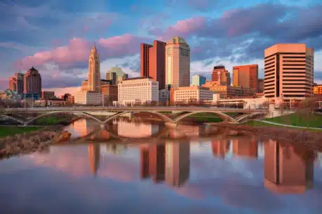 Cityscape image of Columbus, Ohio, USA downtown skyline with the reflection of the city in the Scioto River at spring sunset.