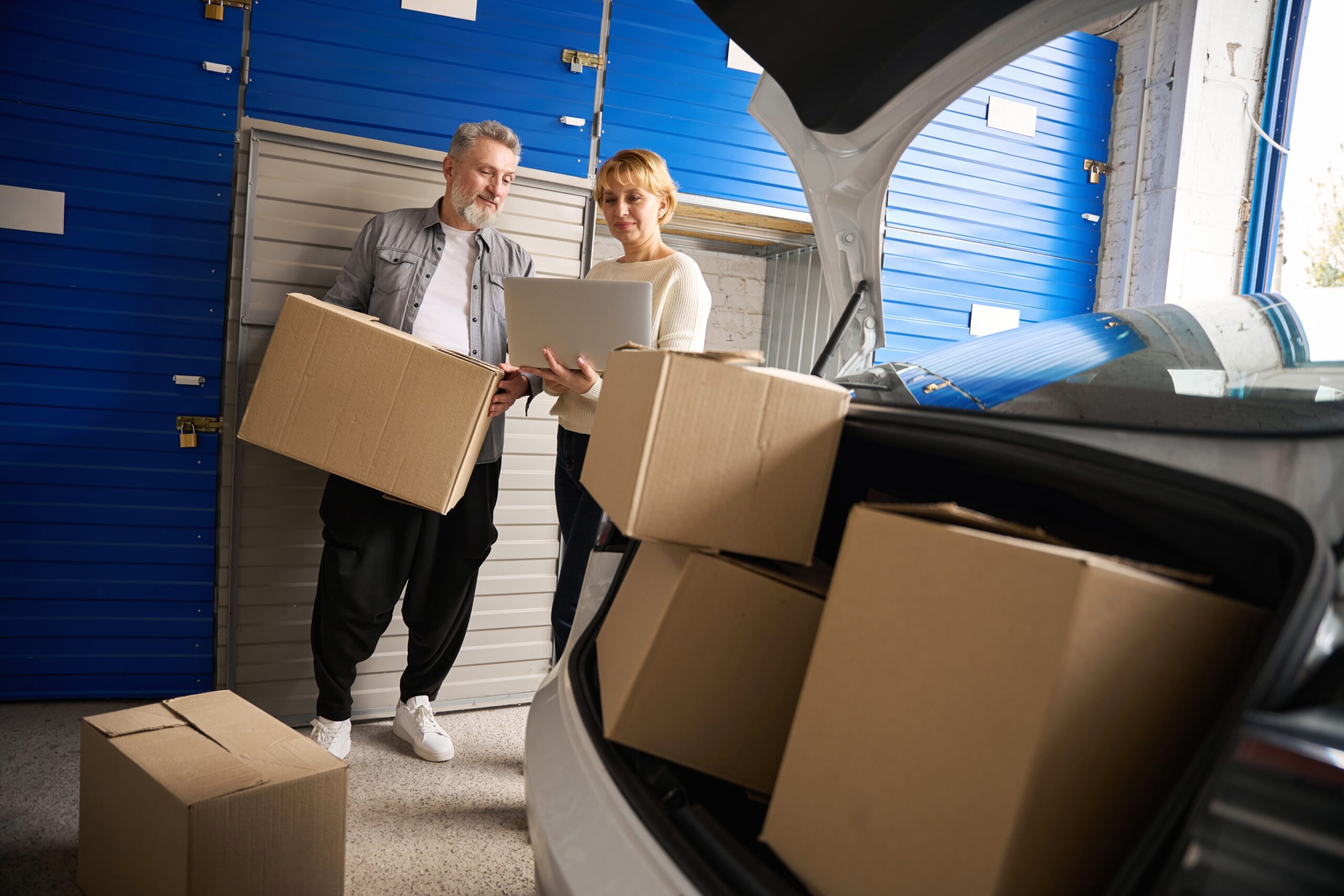 A couple considering drive-up access storage with cardboard boxes in their car