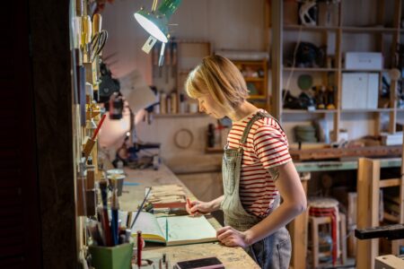 A woman working on her woodworking plans in a workshop