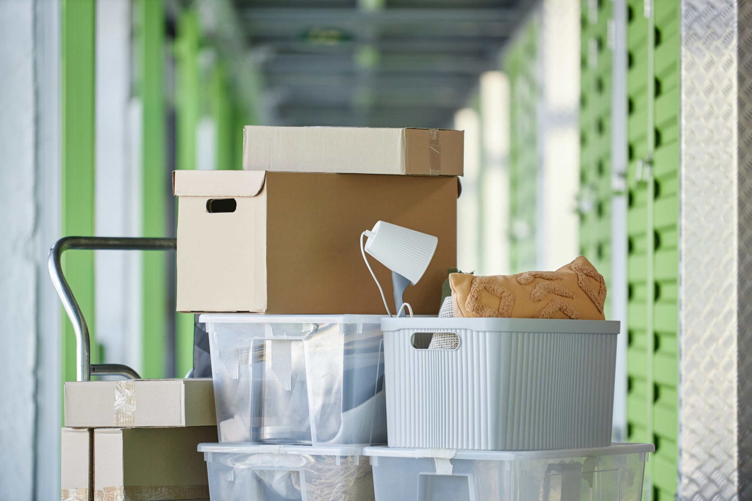 A stack of cardboard boxes and plastic bins on a trolley in a storage facility hallway