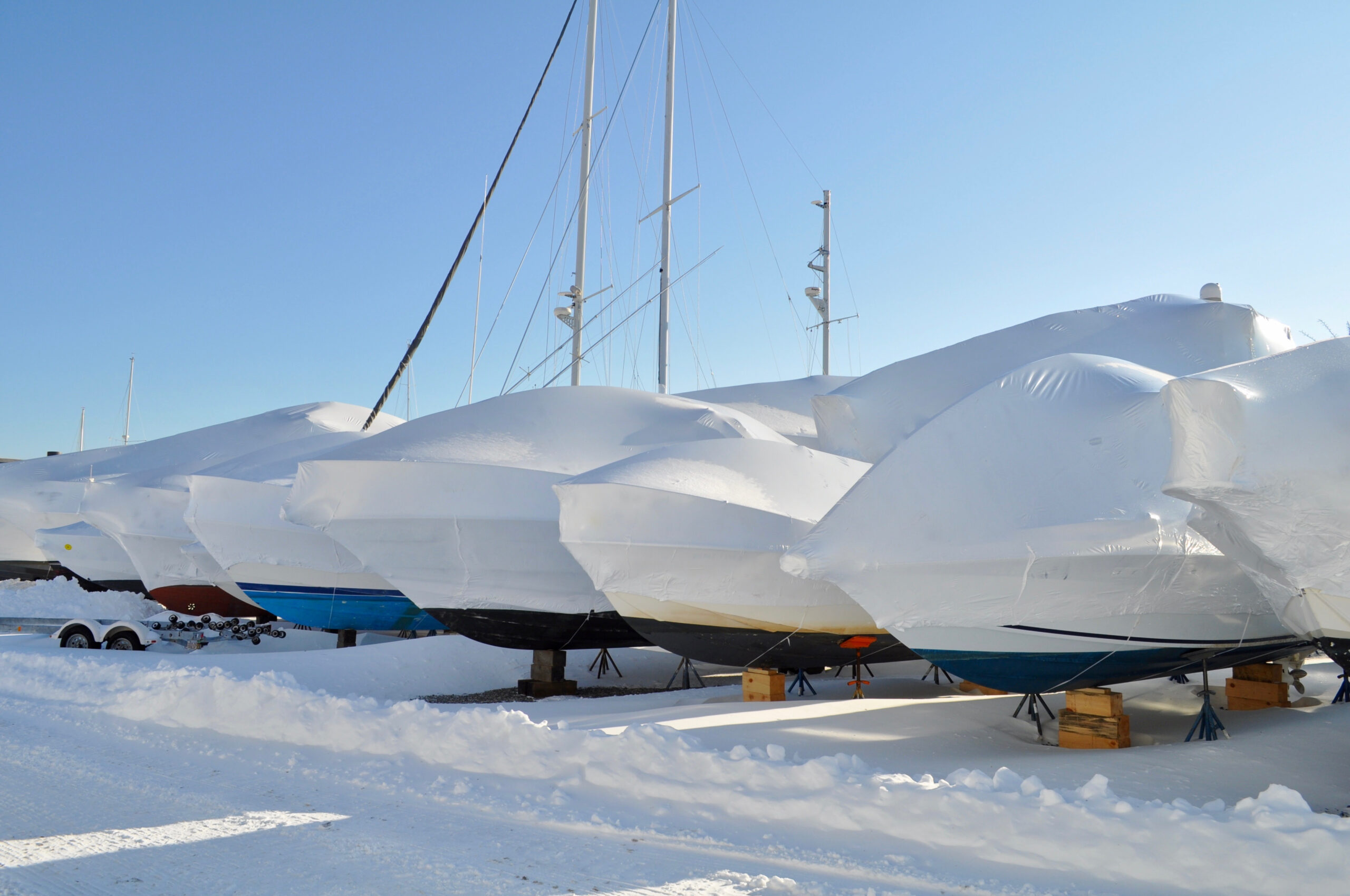 Row of covered boats parked outdoors in the snow