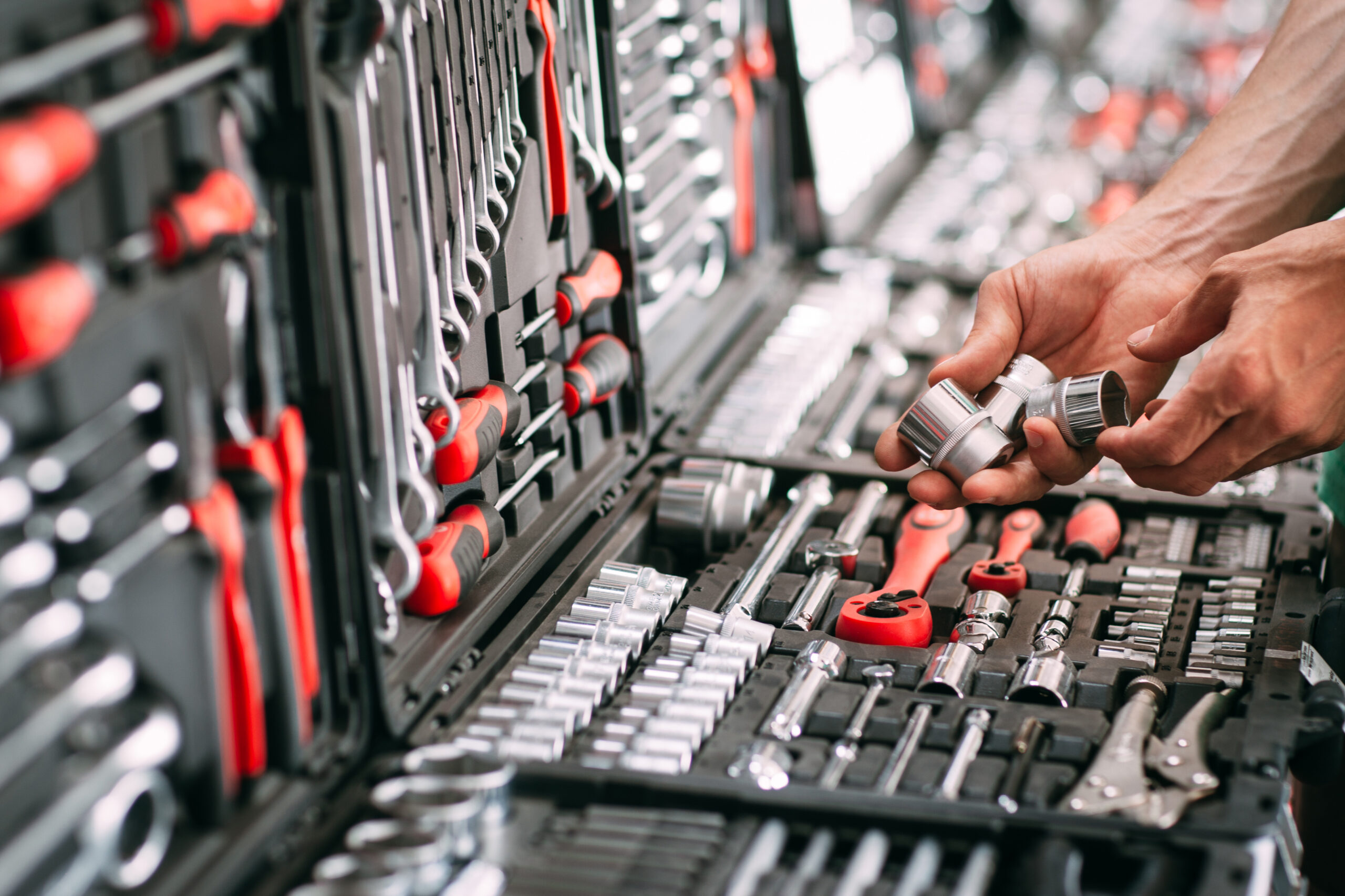 a hand picking out tools from an open tool box