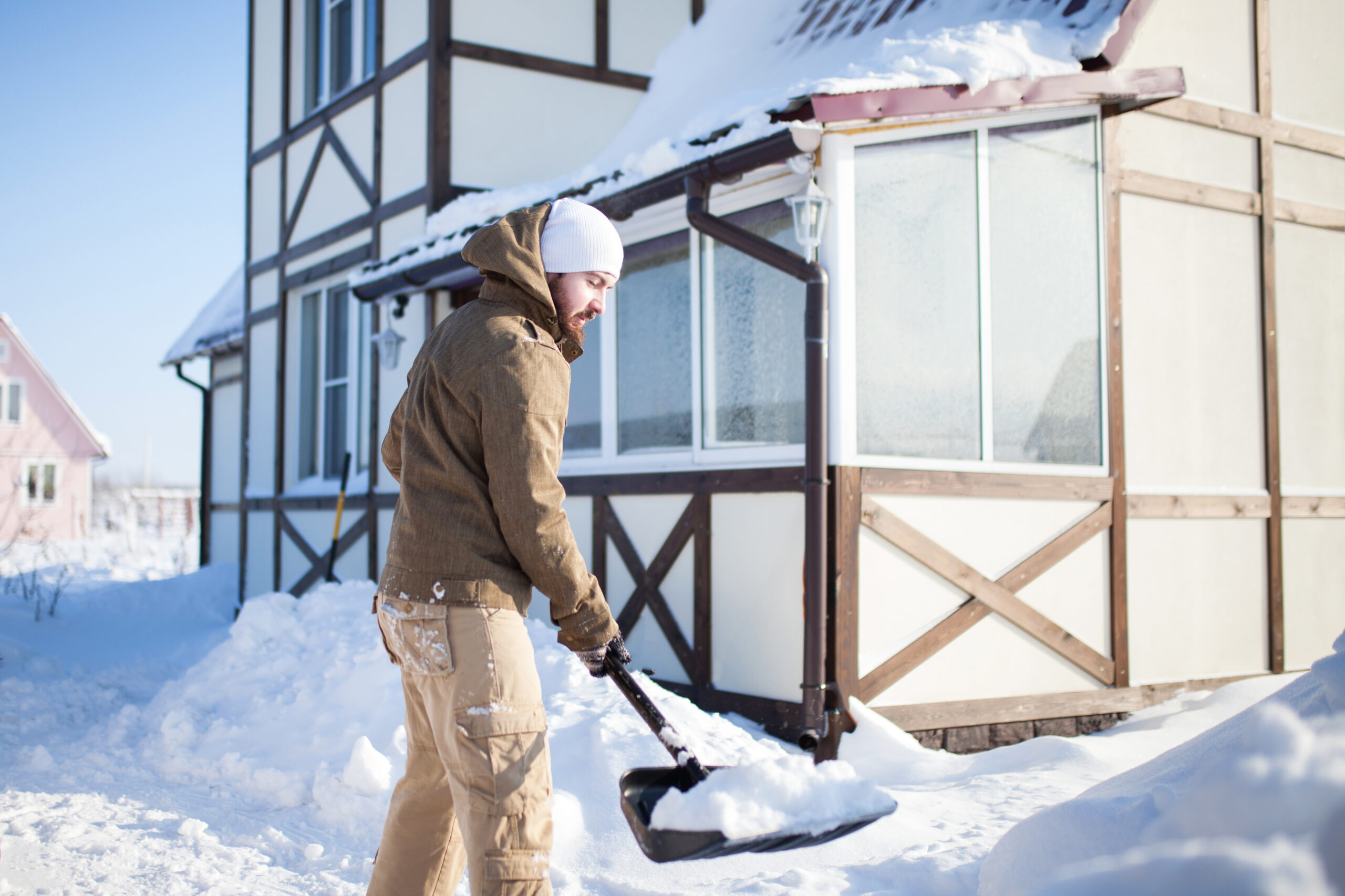 man shoveling snow as part of yearly home maintenance